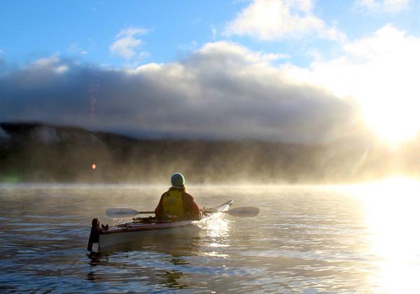 person in kayak on the water at sunrise